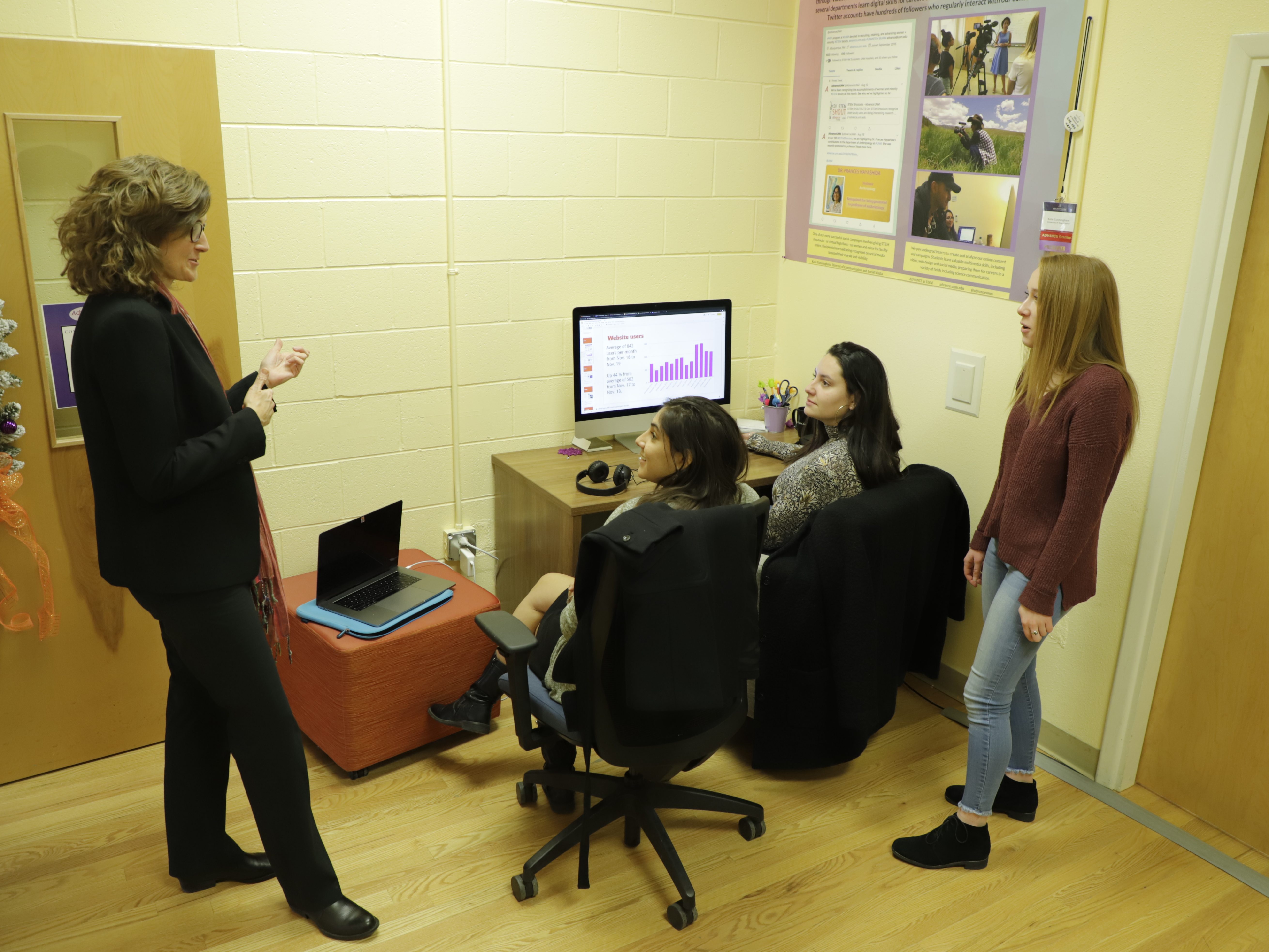 kate_interns A group of co-workers gather around a screen.